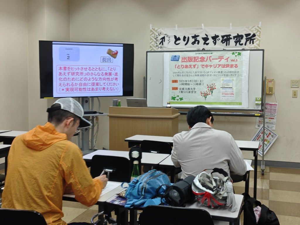机に向かいワークに取り組む参加者と、スクリーン・横断幕のある京都文教大学の会場